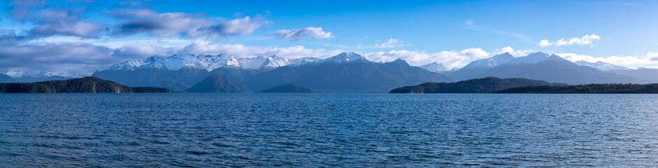 Photograph of a large blue lake and snow-capped mountain range while driving from Te Anau in Fiordland to Manapouri on the South Island of New Zealand
