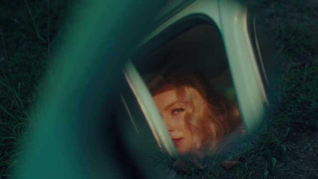 A long-haired blonde is reflected in a retro car mirror