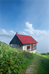 Fototapeta na wymiar Highland landscape in cloudy and foggy weather. Highland houses made of stone and wood. Wooden plateau houses built on the hill. Wooden plateau houses in Turkey. Pokut Plateau Rize Türkiye.