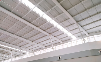 White steel roof and mesh ceiling grille with lay light inside of large modern building, low angle and perspective side view