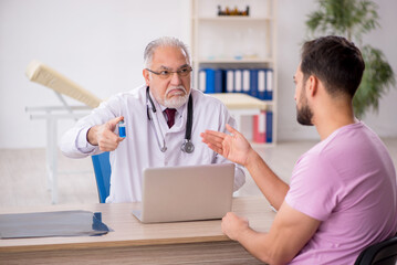 Fototapeta premium Young male patient visiting old male doctor