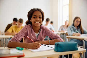 Happy black teenage girl during class at high school looking at camera.