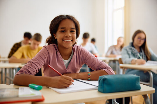 Happy black teenage girl during class at high school looking at camera.