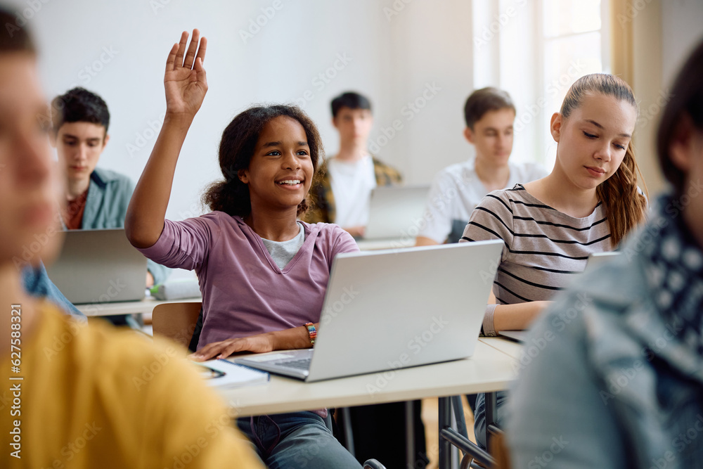 Wall mural happy black high school student raising her arm during computer class in classroom.