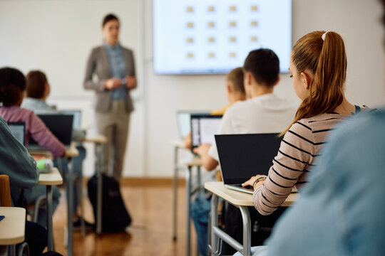 Back View Of Teenage Girl Using Laptop During Computer Class At High School.