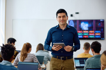 Happy high school teacher in classroom looking at camera.