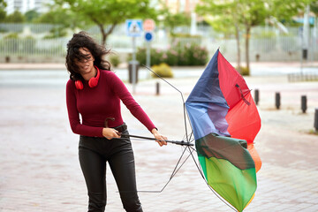 Woman holding a broken umbrella outdoors in rainy day.