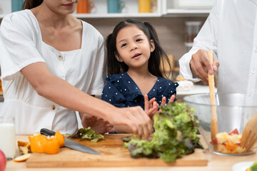 Asia kid girl cooking salad with family in kitchen at home	