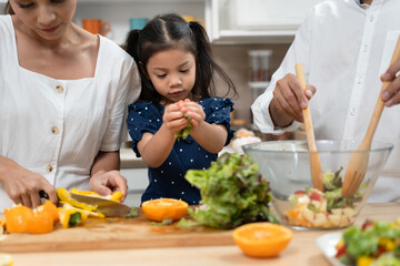 Asia kid girl cooking salad with family in kitchen at home	