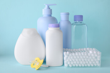 Different skin care products for baby, cotton buds and pacifier on turquoise background. Space for text