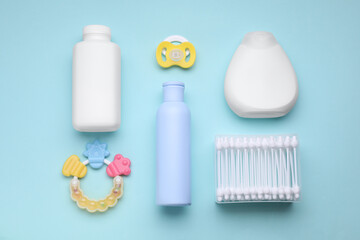 Different skin care products for baby, cotton buds, rattle and pacifier on turquoise background, flat lay