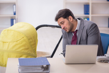 Young male employee looking after newborn at workplace
