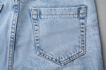 Jeans with pocket on grey background, top view