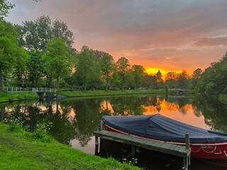 Scenic view of pond with moored boat at sunset