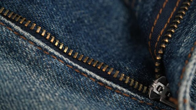 unbuttoned zipper on jeans. rotating the fabric of blue jeans in close-up details. the concept of tailoring. closure, denim texture, abstract background.