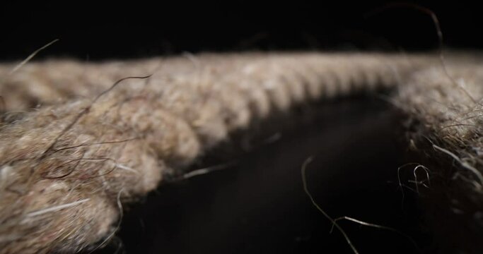 Coil of brown rope on black background. Braided thick rope