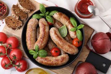 Flat lay composition with tasty homemade sausages, basil leaves and tomatoes in bowl on table
