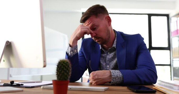 Upset businessman with closed eyes suffering from severe headache or chronic migraine at workplace. Man tired exhausted young man feeling pain in office