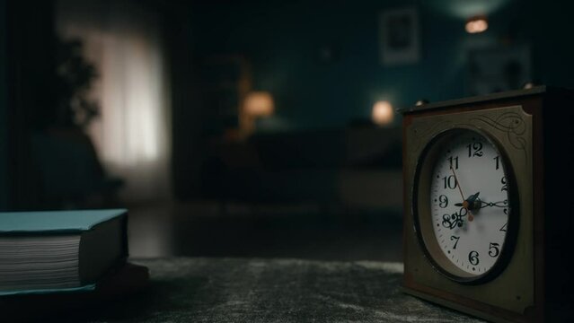 Vintage clock stands on a table in a dark room close up. The clock hand is spinning fast. Time is running out and it cannot be returned, the present becomes the past.