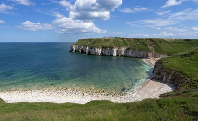 Fototapeta na wymiar Clifftop view of Thornwick Bay and its rocky beach, chalk cliffs and caves. This is a very popular holiday destination in summer. This is on the English Coast Path between Flamborough Head and Bempton