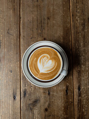Cappuccino on wooden table taken overhead. Heart decoration with the cream. - 627604311