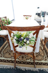 Festive wedding table decoration with flowers hanging from chairs, defocused background