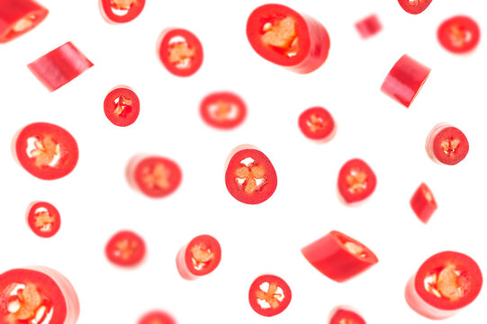 Falling sliced red hot chili peppers isolated on a white background, selective focus.