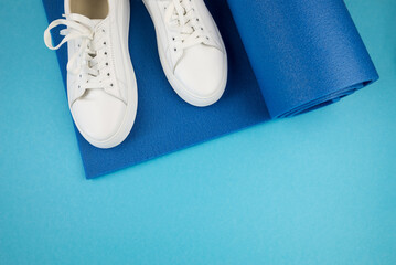 Top view photo of white sneakers and fitness mat.