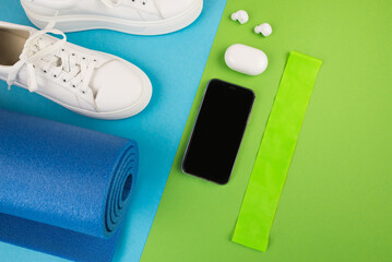 The concept of sports accessories. Photo of blue dumbbells and a blue exercise mat, white sneakers and other sports equipment.