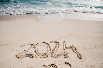 2024 written in white sand on tropical beach, happy New Year