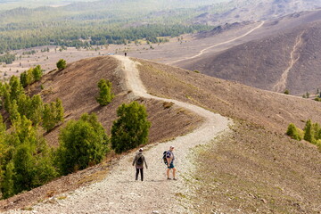 man and woman tourists stand on the top of Poklonnaya Gora against the background of Mount Karabash on a summer day. Chelyabinsk region. Russia