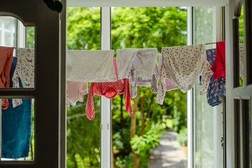 Baby clothes hanging on the clothesline. Toddlers clothes drying on the balcony. Rope with clean...