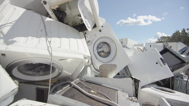 White discarded appliances dumped onto pile at disposal centre, slider