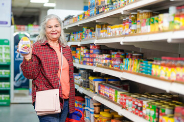 senior indian woman showing product at grocery shop.