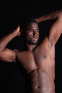 Young black man with hands behind head and showing abs in light