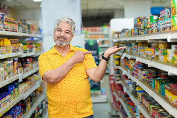Senior indian man giving expression while purchasing at grocery shop.
