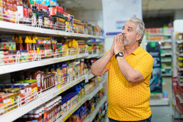 Senior indian man shocking expression on inflation at grocery shop.