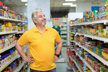 Senior indian man giving expression while purchasing at grocery shop.