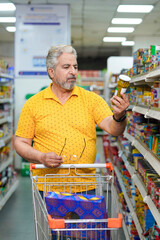 Senior man looking product detail and purchasing at grocery shop.