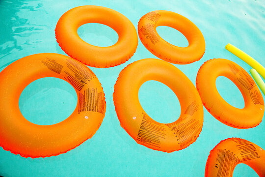 Orange lifesaver floaties in a blue pool of water