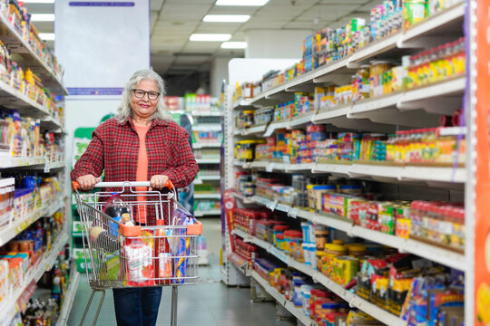 senior indian woman purchasing at grocery shop.