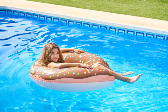 Adorable girl sitting in floater over swimming pool