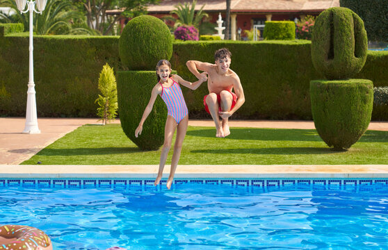 Cheerful preteen in swimsuit jumping into pool