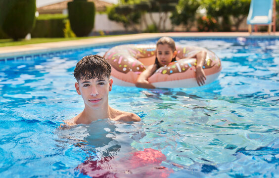 Confident kids playing in floater on swimming pool