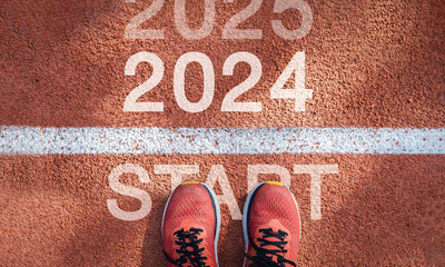 New year 2024 concept, beginning of success. Text 2024 written on asphalt road and male runner preparing for the new year. Concept of challenge or career path and change.