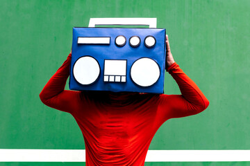 Anonymous person covering face with blue boombox