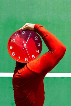 Anonymous person covering face with red clock