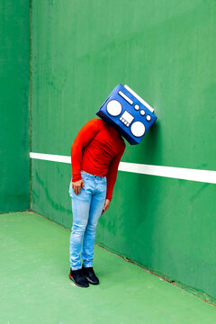 Upset unrecognizable person with boombox against wall