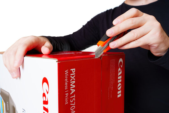 Kyiv, Ukraine - July 20, 2023: Person Using a Utility Knife to Open a Red and White Canon Pinter Retail Box