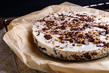 Homemade brownie chocolate cake with coffee cream and walnuts on baking paper.